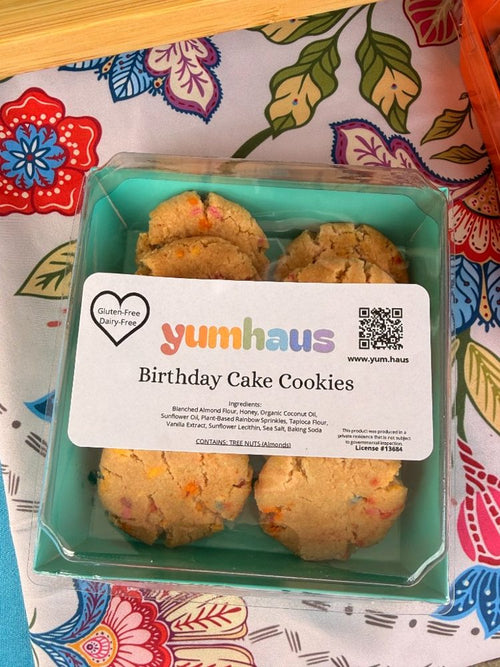 A box of Yumhaus gluten-free, dairy-free Birthday Cake cookies with rainbow sprinkles in a teal box